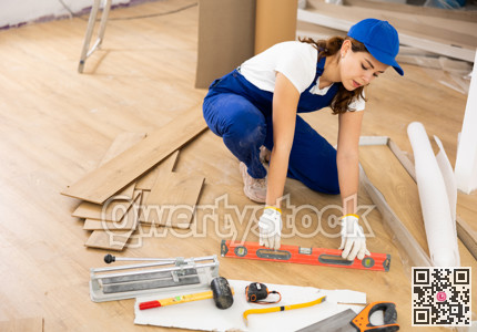 Woman builder puts laminate on the floor in room