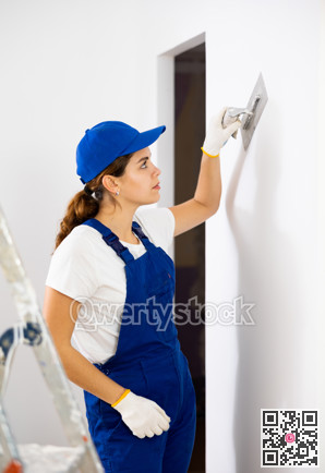 Woman applying plaster to a wall with floated trowel