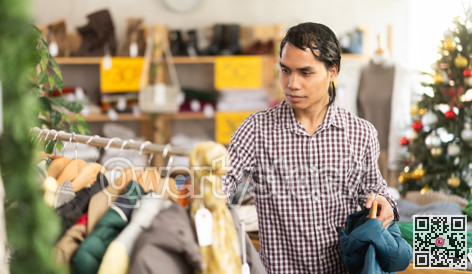 In chain shop, Indonesian man choose down jacket or rain coat, X mas shopping