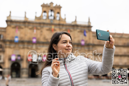 Woman is taking photos on her camera while journey through the Plaza Mayor. Spain