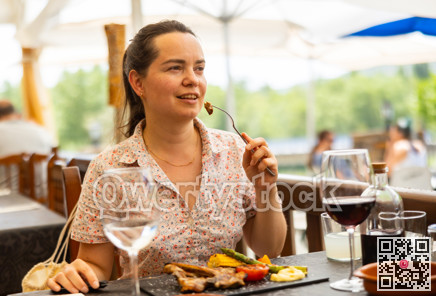 Woman eating hot dish of lamb in restaurant on an outdoor terrace