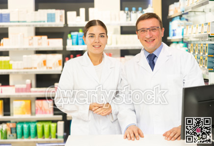 Young girl and middle-aged man pharmacists posing together in chemist's shop