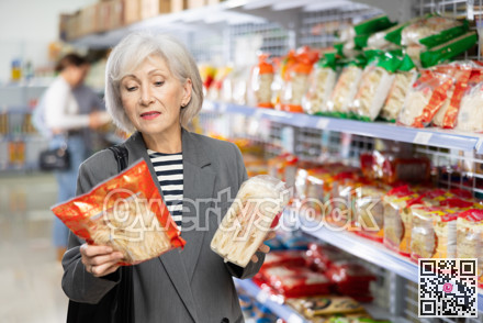 Senior woman in supermarket buys daily groceries, pasta Chinese noodles