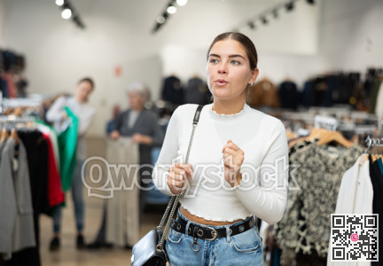Young girl watching excitedly large stock of clothes in clothing store