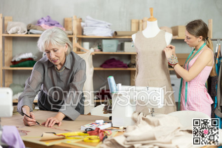 Mature female dressmaker drawing on paper other work with mannequin