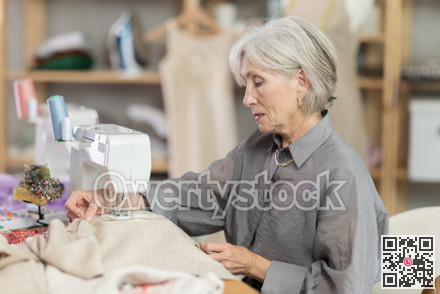 Woman seamstress sews on sewing machine in workshop