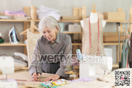 Woman dressmaker drawing pattern on paper in workshop