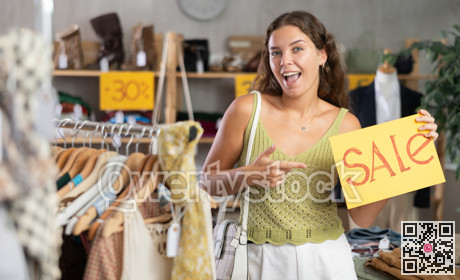 Young woman holding sale sign in clothing store