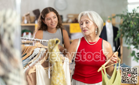 Two positive women choosing something for summer in clothing store