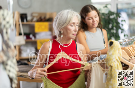 Two happy women of different ages choose summer clothes in fashion boutique