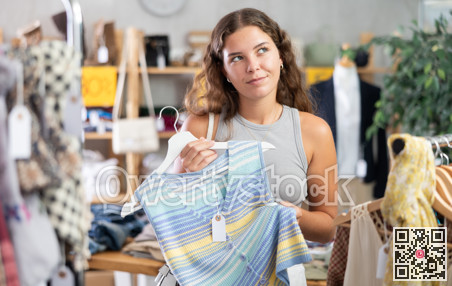 Young woman choosing vest in clothing store