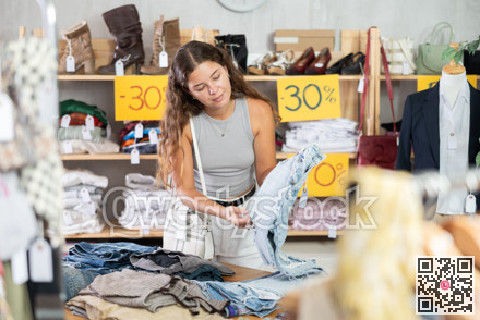 Young woman choosing jeans in clothing store