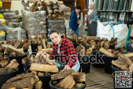 Girl chooses and buys a bundle of firewood at hardware store.