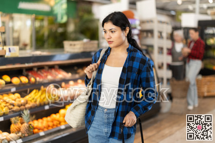 Woman in supermarket sales area looks into distance and searches for necessary goods