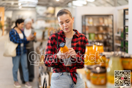 Young woman chooses juice at grocery store