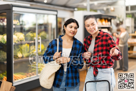 Two young women talk and choosing food in grocery store