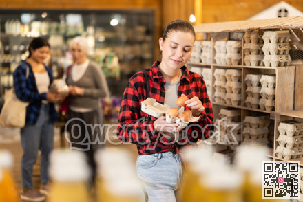 Girl selects and buys chicken eggs at grocery supermarket.