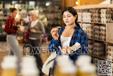 Young woman choosing eggs at grocery store