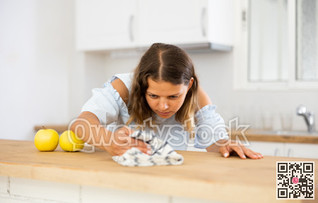 Positive woman cleaning kitchen table at home