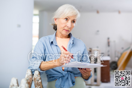 Mature woman making notes at renovating house