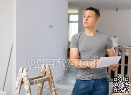Young man checking project documentation in apartment during repair works