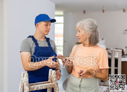 Senior woman paying wage to teenage boy assistant in construction site
