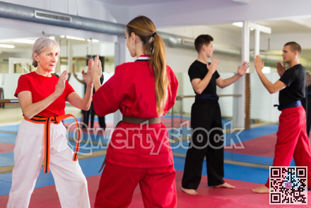 Senior and younger women sparring during group karate training