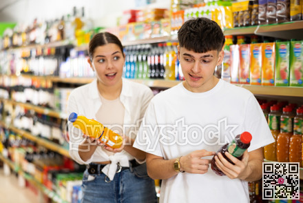 Young couple of customers diligently picking out soft drinks