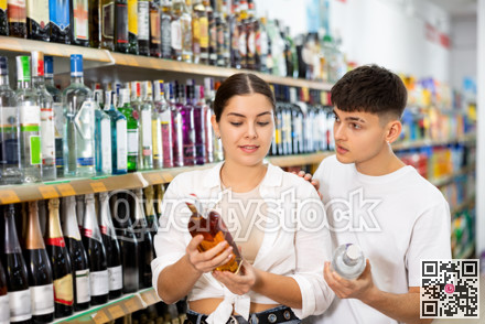 Man and woman choose high-quality alcoholic drink in supermarket
