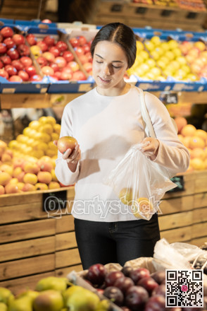 Young woman chooses lemons in vegetable shop