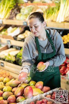 Young woman seller puts mangoes in store