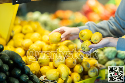Shopper selects ripe lemons at a grocery supermarket close up