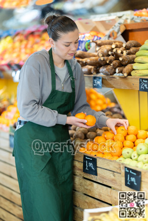 Female salesperson places tangerines on display case