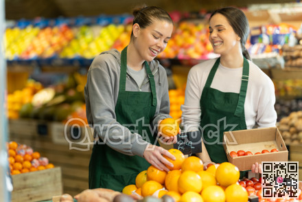Two sellers place oranges and tomatoes on store counter