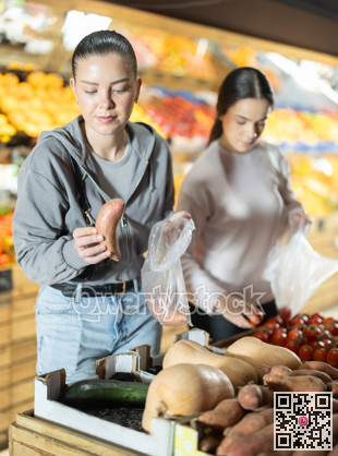 Two young women choosing cassava at vegetable store