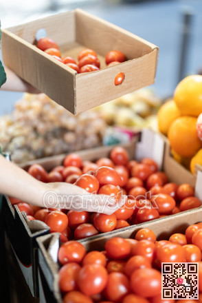 Closeup of seller hands put ripe red tomatoes on grocery supermarket display