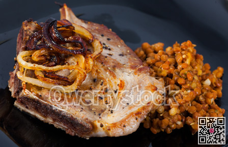 Close up of tasty fried pork with lentils at black plate