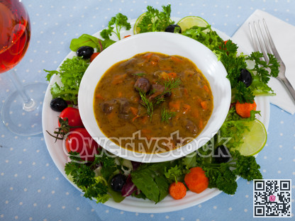 Tasty goulash from chicken hearts with lettuce at plate, fresh vegetables