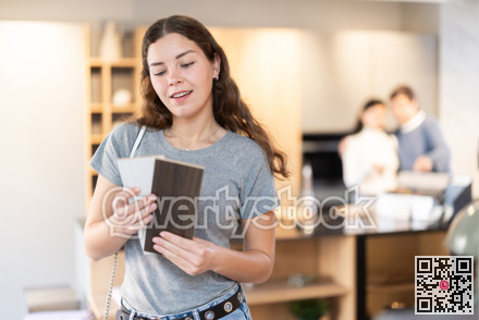 Female buyer with samples of material chooses kitchen set in furniture store