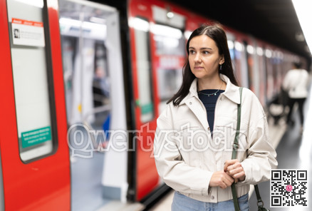 Girl is standing on metro platform station, waiting for transport to arrive