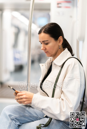 Girl in modern subway car scrolling smartphone