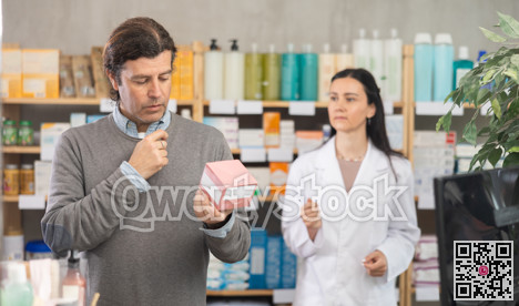 Middle-aged man choosing pills in box while pharmacist offering in drugstore