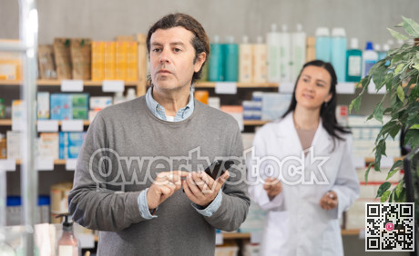 Adult man with phone choosing medicines and hygiene products