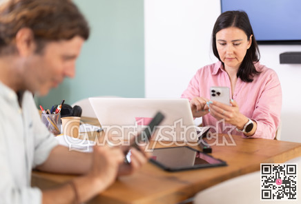 Middle-aged woman is on smartphone at workplace