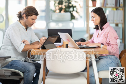 Woman working on laptop and man working on tablet in office