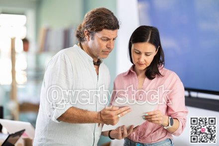 Adult man and woman colleagues discussing document