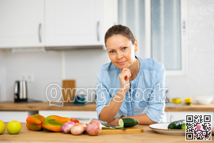 Smiling woman holding face with hand in kitchen at home