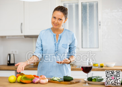 Positive young adult woman posing in kitchen