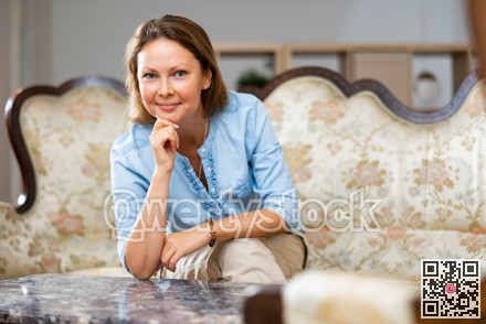 Positive woman sitting on sofa at home
