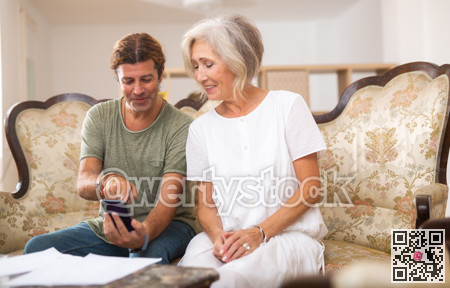 Wife and husband couple using smart phone watching videos, social media, reading news on cellphone at home